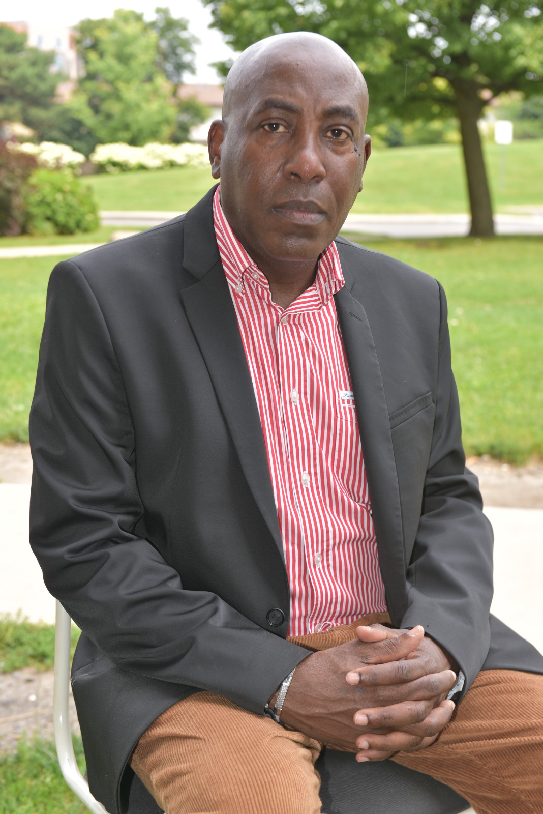 Jules Ruhinda seated outdoors in a suit jacket